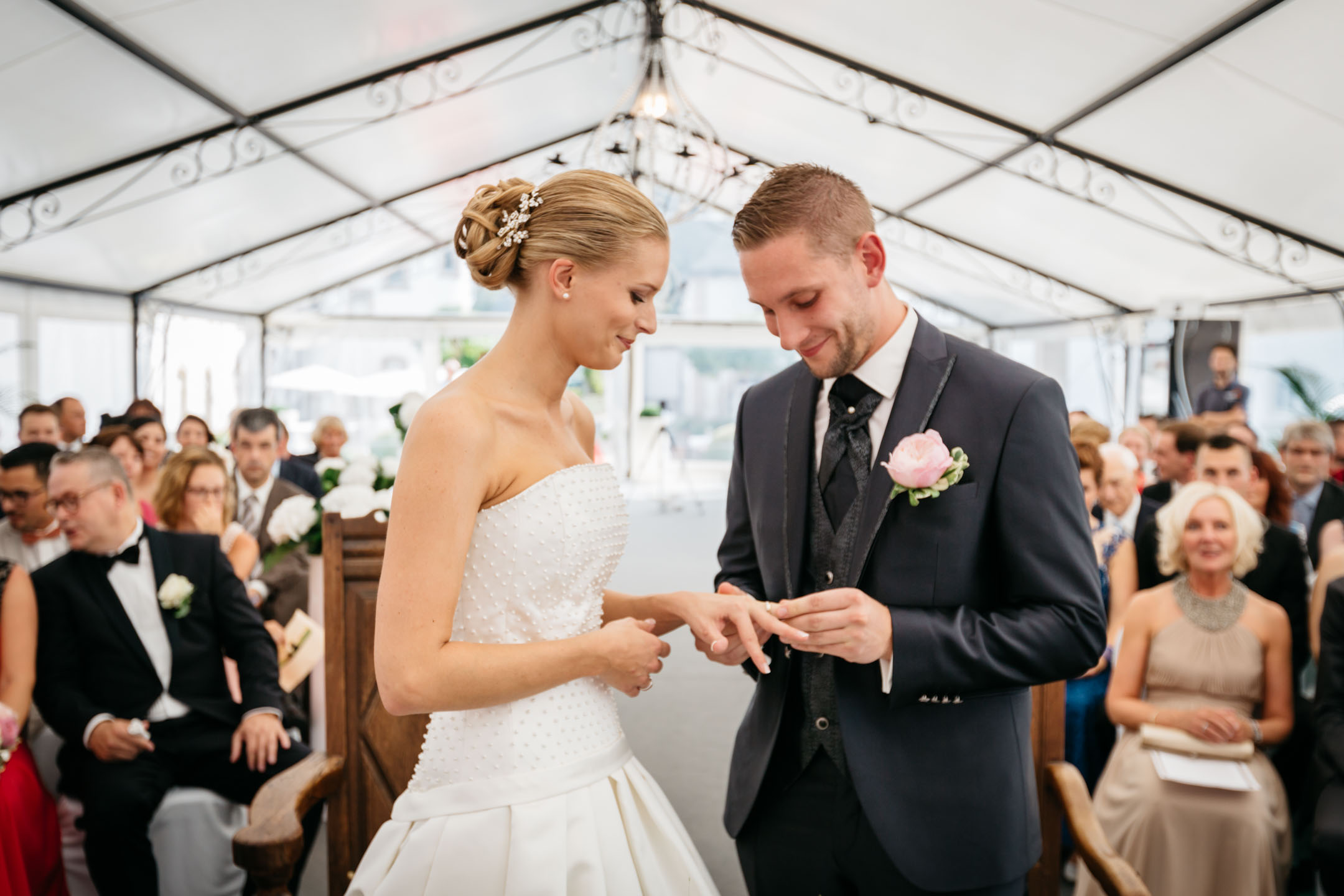 Photo du moment où le marié passe la bague au doigt de la mariée